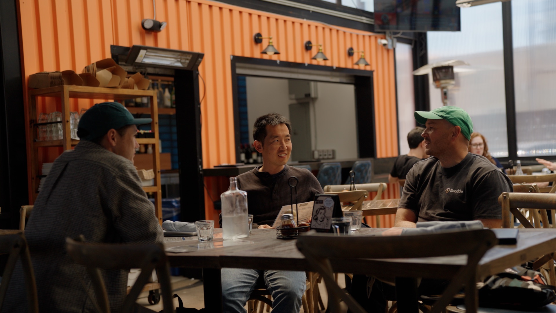 Toby and Seb talking with a guest at a restaurant table
